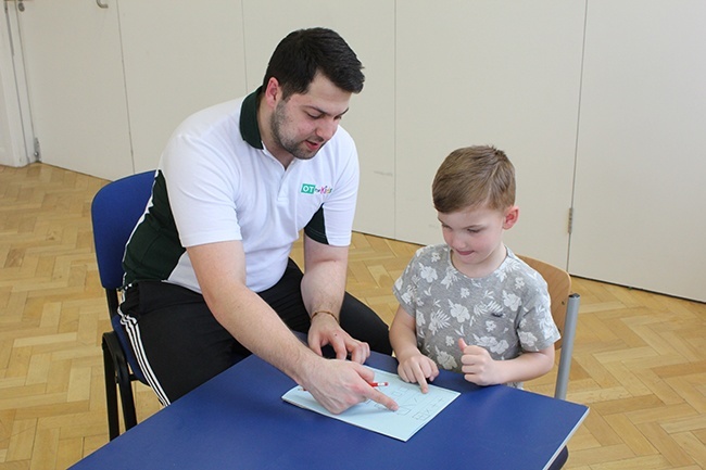 Therapist demonstrating how to use the assessment to child 
