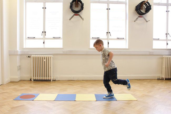Small boy hopping along a coloured mat