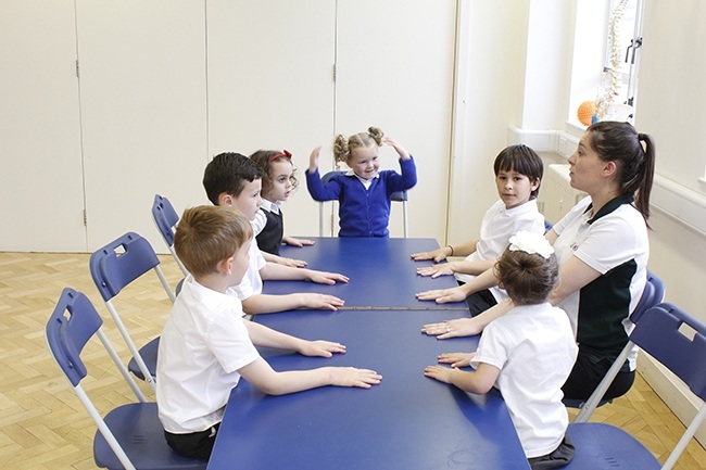 Child balancing on board, therapist providing support at the hips 