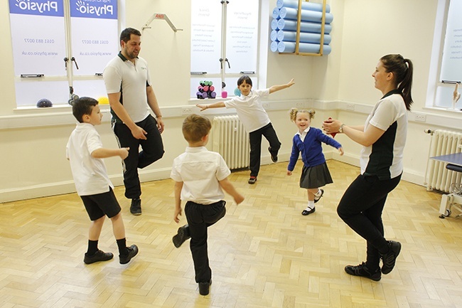 Child balancing on board, therapist providing support at the hips 