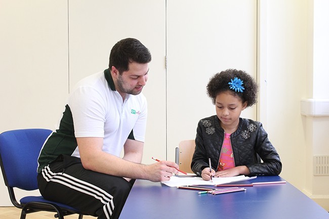 Child completing writing assessment, therapist observing