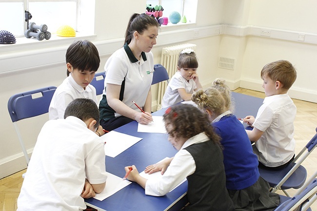 Children writing in a group, therapist observing