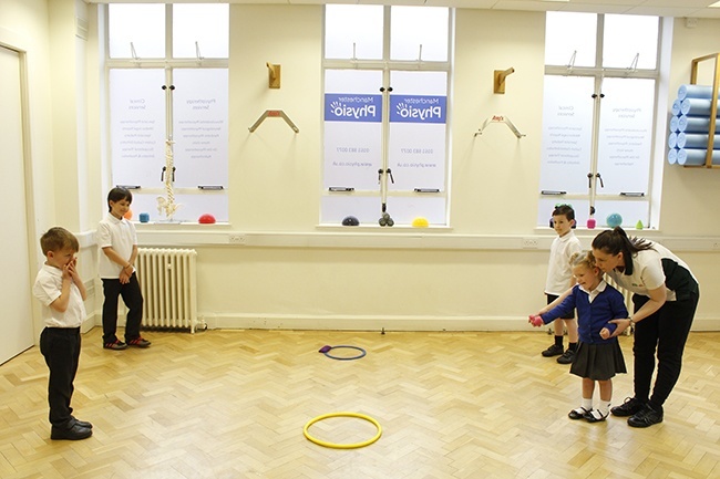 Therapist showing child how to throw a ball, 3 other children watching