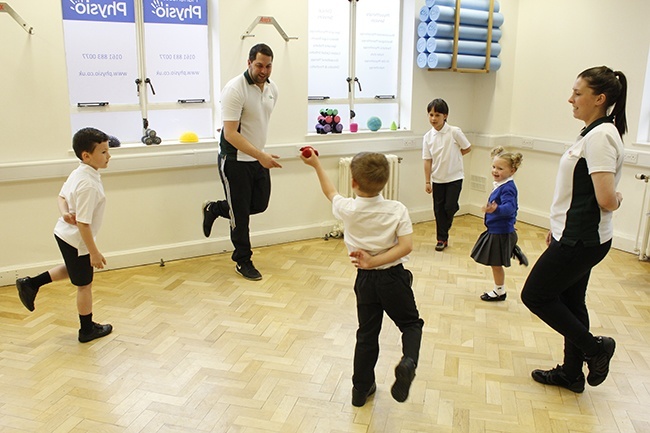 Children throwing beanbag, stood on one leg in a group