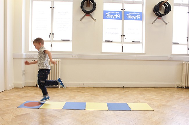 Child hopping onto red target mat