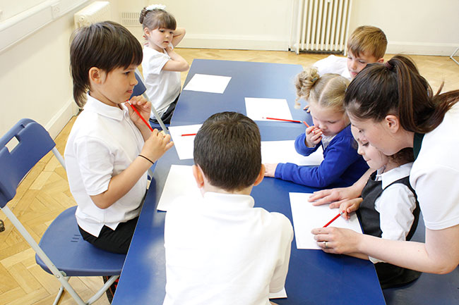 Therapist working with child on improving writing. Other children in group observing