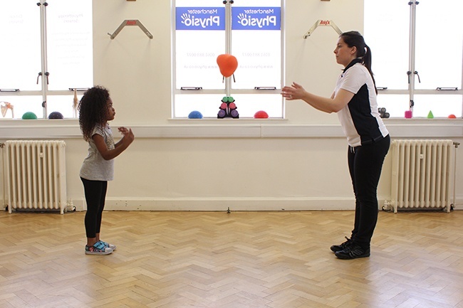 Therapist throwing a ball to child 